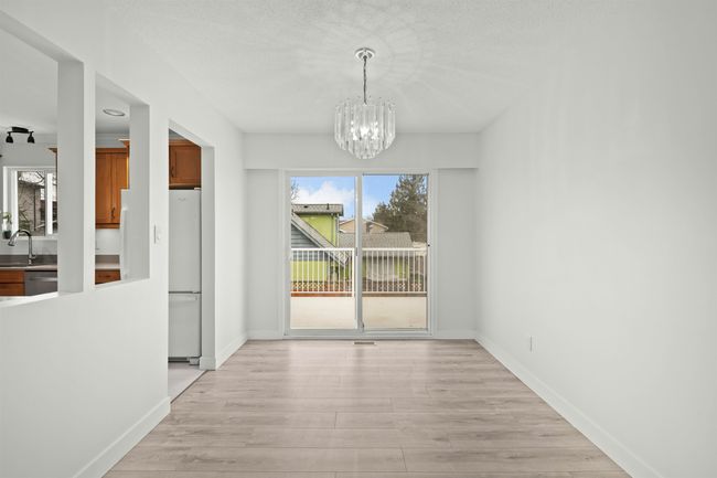 Unfurnished dining area with baseboards, light wood-type flooring, a sink, and an inviting chandelier | Image 7
