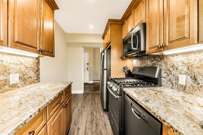 Kitchen with appliances with stainless steel finishes, light stone countertops, light wood-style floors, and backsplash | Image 7