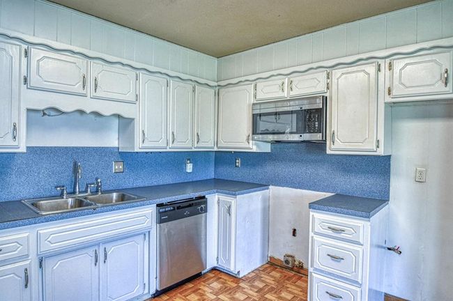 Kitchen with stainless steel appliances, a sink, and dark countertops | Image 8