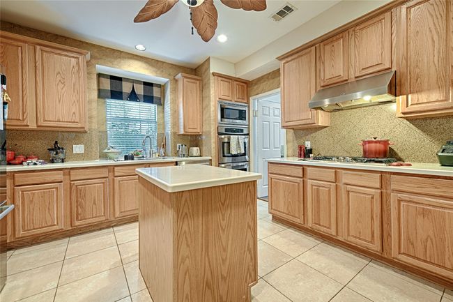 Kitchen with appliances with stainless steel finishes, light tile patterned floors, visible vents, and exhaust hood | Image 28