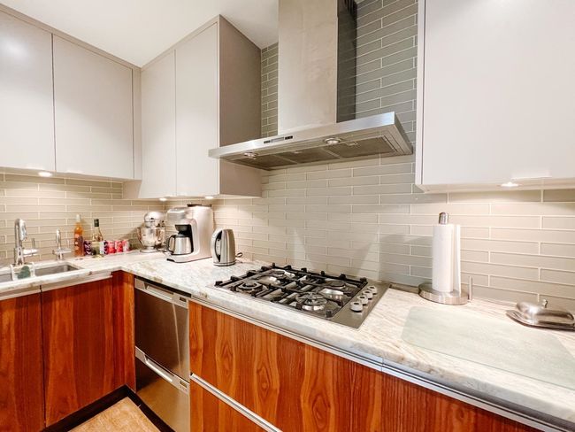 Kitchen featuring wall chimney exhaust hood, stainless steel appliances, a sink, and backsplash | Image 14