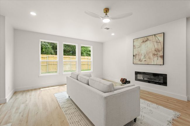 Living room featuring light wood-style floors, a ceiling fan, baseboards, a glass covered fireplace, and recessed lighting | Image 8