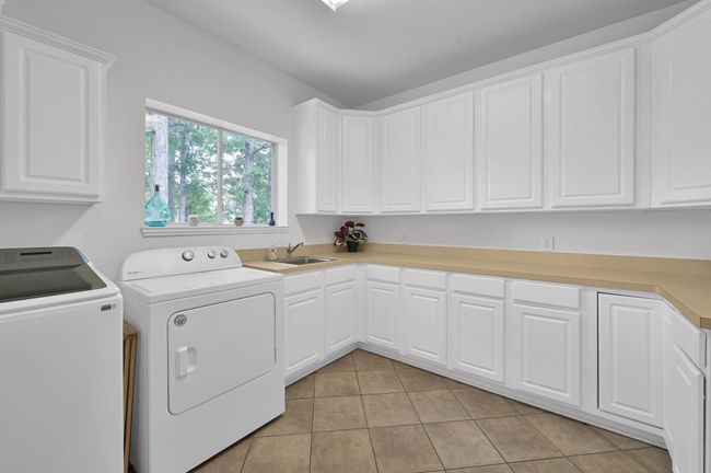 Another outstanding feature in this home! The laundry room features an IMPRESSIVE extra-long counter cabinet, ideal for folding and storage. To the right (not pictured), there is a space for second fridge. | Image 36