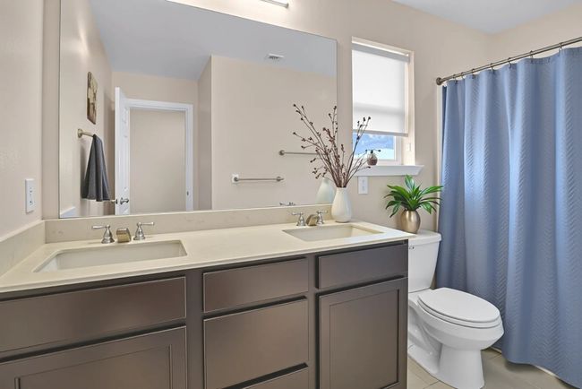 *Virtual Staged Full bathroom upstairs* featuring toilet, double vanity, tile patterned floors, and curtained shower | Image 21