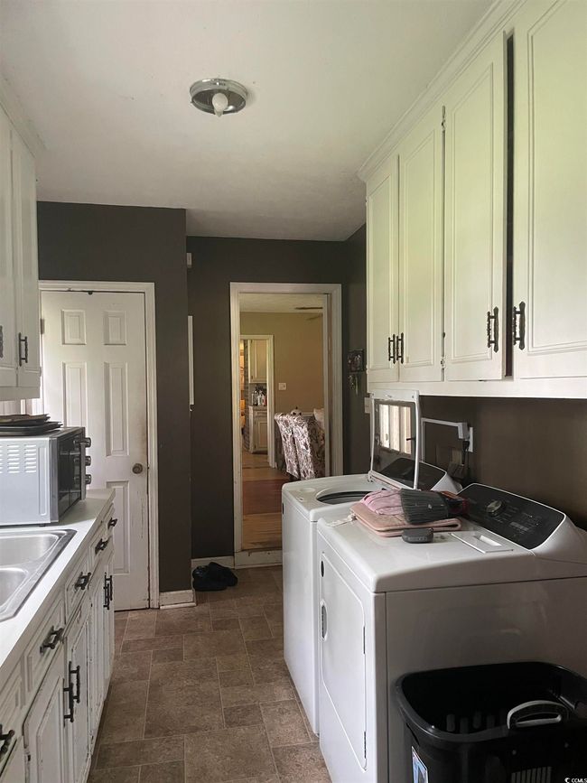 Laundry room featuring independent washer and dryer, cabinet space, and stone finish floors | Image 20