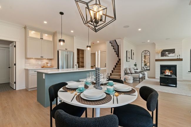 Dining space featuring light wood-style floors, a chandelier, ornamental molding, recessed lighting, and stairs | Image 9