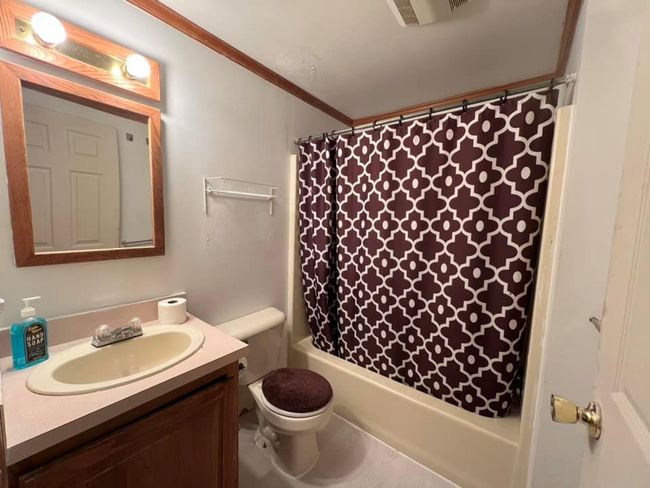 Full bathroom with vanity, toilet, shower / bath combo with shower curtain, and crown molding | Image 9