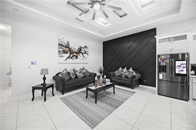 Living room featuring light marble finish floors, an accent wall, a raised ceiling, baseboards, and a ceiling fan | Image 21
