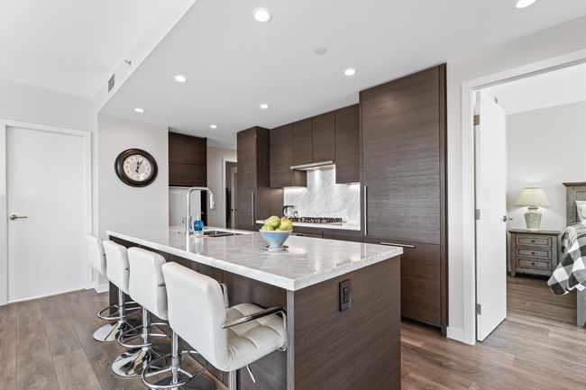 Kitchen featuring a sink, modern cabinets, dark brown cabinetry, a kitchen bar, and dark wood finished floors | Image 7