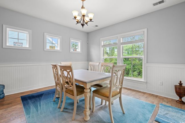 Dining area featuring a wainscoted wall, a chandelier, and wood finished floors | Image 11