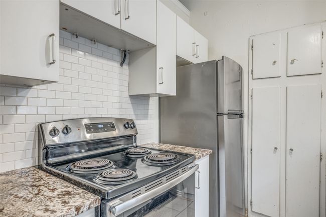 Kitchen featuring stainless steel appliances, white cabinets, and backsplash | Image 11