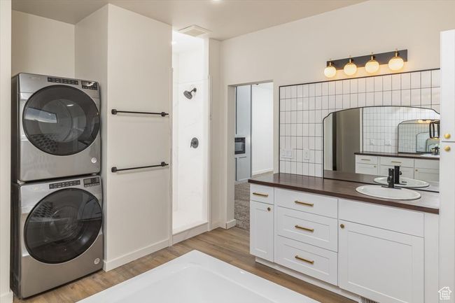 Washroom with sink, stacked washing maching and dryer, and light hardwood / wood-style flooring | Image 24