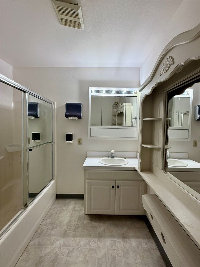Full bathroom featuring visible vents, shower / bath combination with glass door, vanity, and a textured ceiling | Image 13
