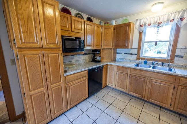 Kitchen featuring black appliances, sink, light tile patterned floors, and tasteful backsplash | Image 6