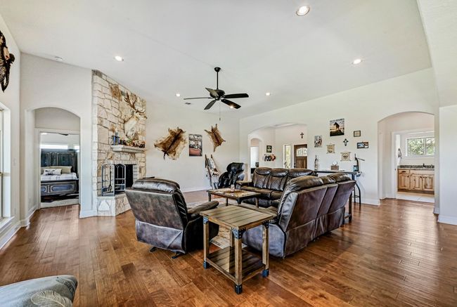 Living area featuring a ceiling fan, wood-type flooring, a fireplace, arched walkways, and recessed lighting | Image 6