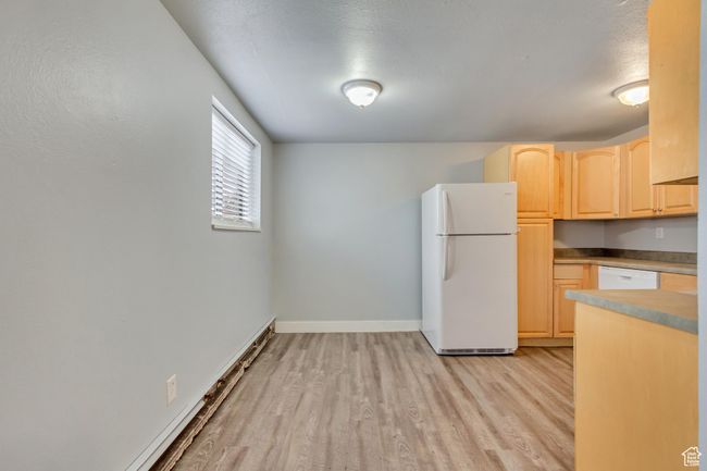 Kitchen with white appliances, light brown cabinets, light wood finished floors, and baseboards | Image 7