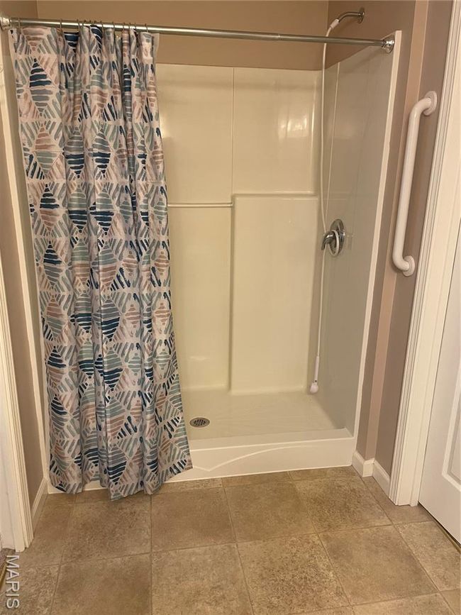 Full bathroom featuring a shower with shower curtain, baseboards, and tile patterned floors | Image 13