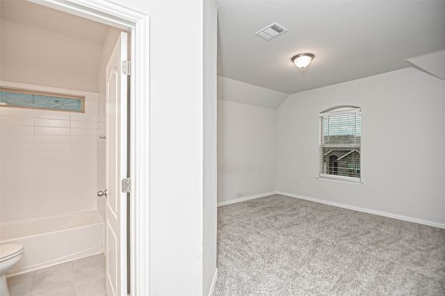 Empty room featuring visible vents, vaulted ceiling, light tile patterned floors, and light colored carpet | Image 26