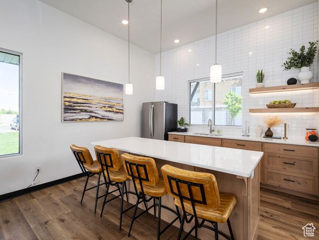 Kitchen featuring dark wood-type flooring, freestanding refrigerator, a sink, and decorative backsplash | Image 18