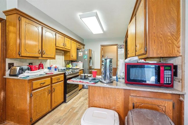 Kitchen with appliances with stainless steel finishes, light wood finished floors, brown cabinetry, and a peninsula | Image 13