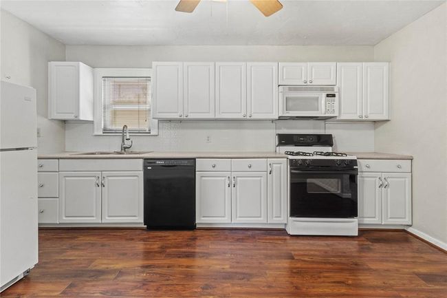 Kitchen with ceiling fan, white cabinets, white appliances, sink, and dark hardwood / wood-style floors | Image 21