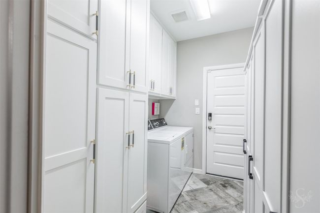 The laundry room features upgraded cabinets, providing excellent storage solutions. This addition enhances the room's functionality while maintaining a modern and tidy appearance. | Image 25