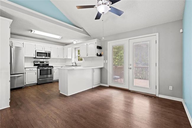 Kitchen featuring stainless steel appliances, a peninsula, vaulted ceiling, healthy amount of natural light, and white cabinetry | Image 14