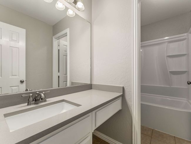Bathroom with tile patterned flooring, vanity, bathtub / shower combination, and a textured wall | Image 34