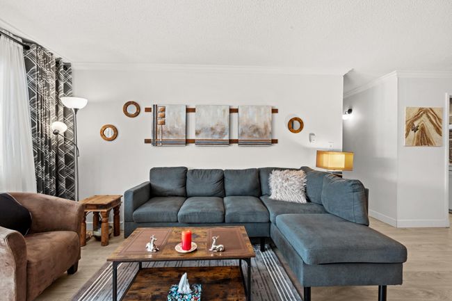 Living room with a textured ceiling, baseboards, light wood-type flooring, and ornamental molding | Image 4
