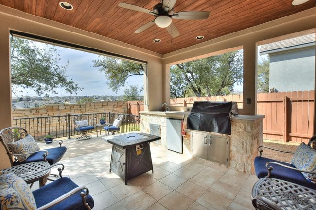 View of patio featuring a fenced backyard, ceiling fan, a sink, a fire pit, and grilling area | Image 30