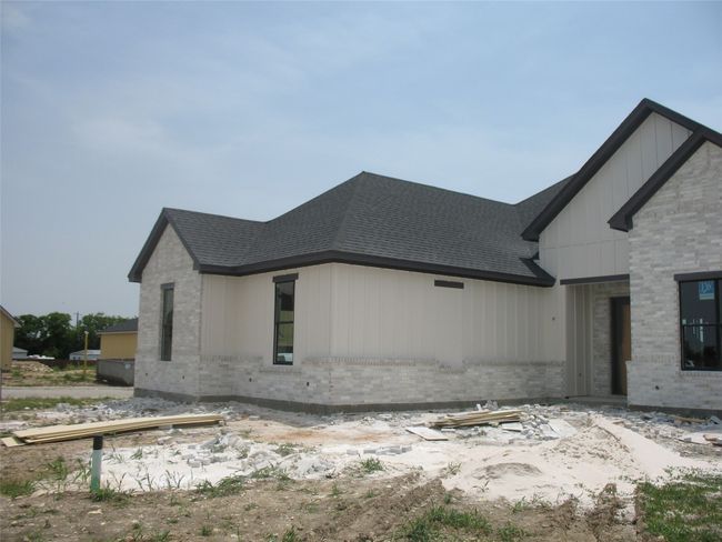 View of home's exterior featuring brick siding, a shingled roof, and board and batten siding | Image 4