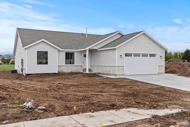Single story home with stone siding, a shingled roof, an attached garage, concrete driveway, and cooling unit | Image 23