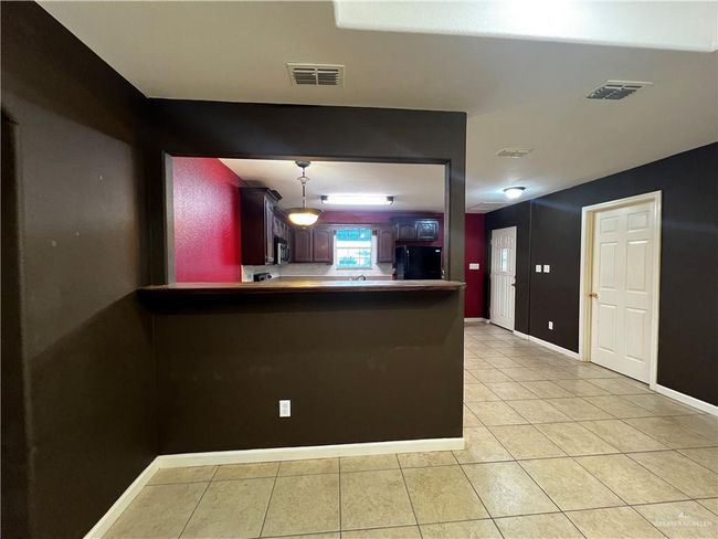 Kitchen with freestanding refrigerator, light tile patterned floors, baseboards, a peninsula, and stainless steel microwave | Image 5