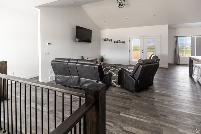 Living room featuring dark wood-type flooring, french doors, vaulted ceiling, and baseboards | Image 5
