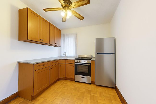 Kitchen featuring appliances with stainless steel finishes, light countertops, a ceiling fan, and brown cabinetry | Image 24