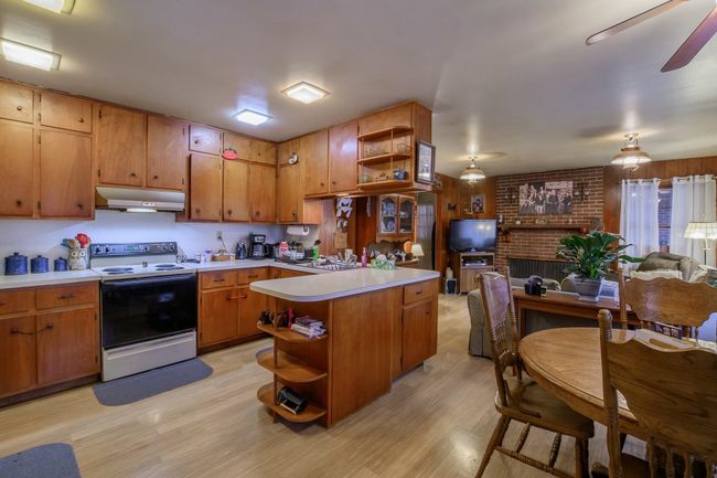 The kitchen opens to the Family Room and it's cozy wood-burning brick fireplace. Eat-in area by the kitchen. | Image 6