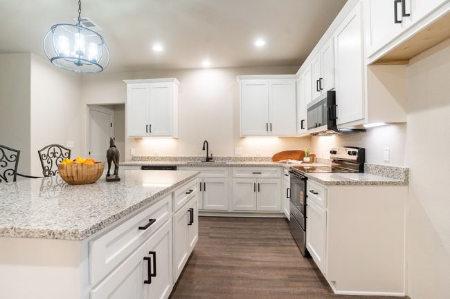 Kitchen featuring stainless steel appliances, a sink, white cabinets, dark wood-style flooring, and recessed lighting | Image 8