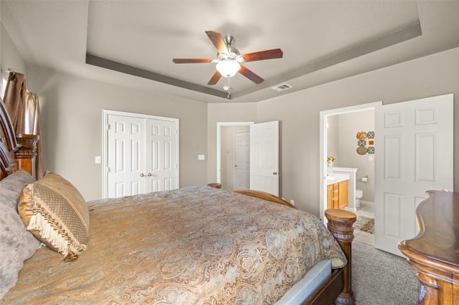 Master Bedroom featuring a tray ceiling, a closet, ensuite bath, and a ceiling fan | Image 15