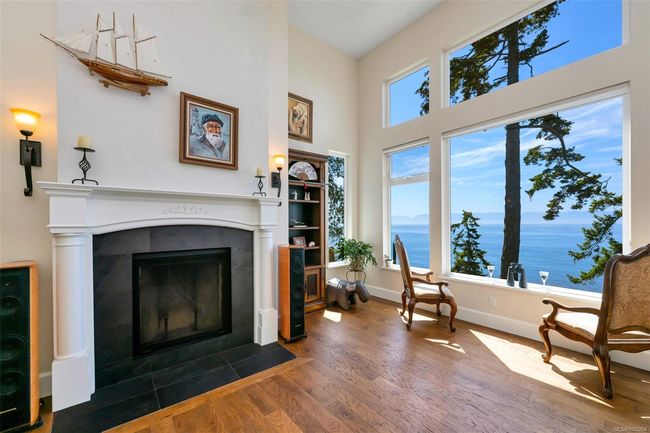 Sitting room with a fireplace, wood finished floors, a high ceiling, and a water view | Image 39