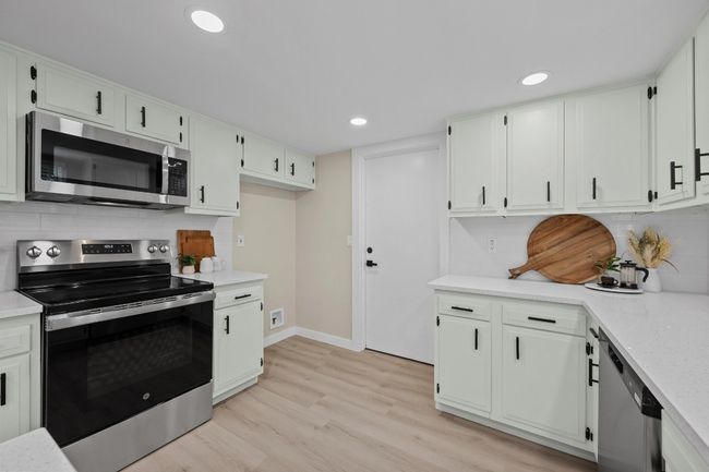 Kitchen featuring backsplash, light countertops, light wood-style flooring, and appliances with stainless steel finishes | Image 8