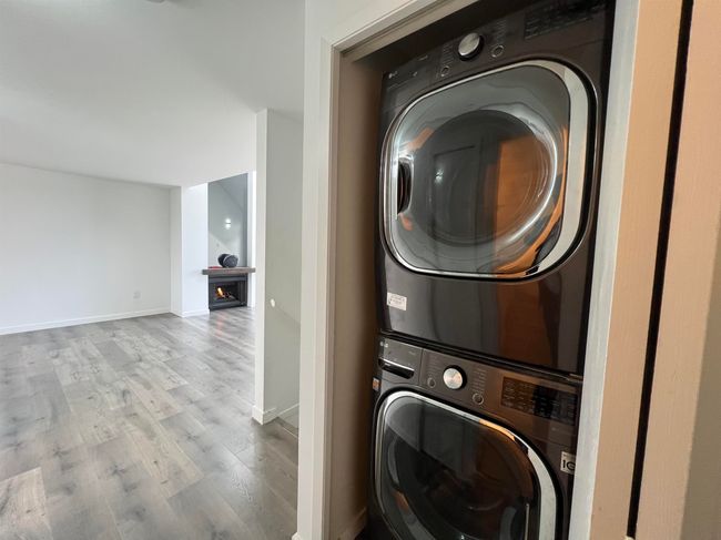 Washroom with stacked washer and clothes dryer and wood finished floors | Image 18