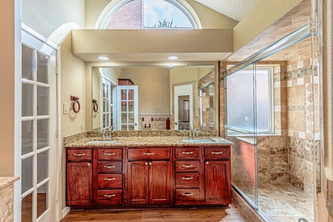 Bathroom featuring double vanity, wood finished floors, a stall shower, and vaulted ceiling | Image 19
