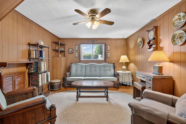 Living area with ceiling fan, wood finished floors, and wood walls | Image 7