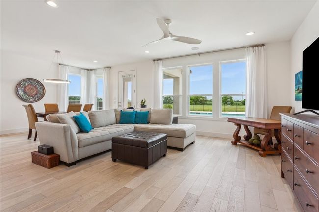 Living room with light wood-type flooring, healthy amount of natural light, baseboards, recessed lighting, and ceiling fan | Image 12