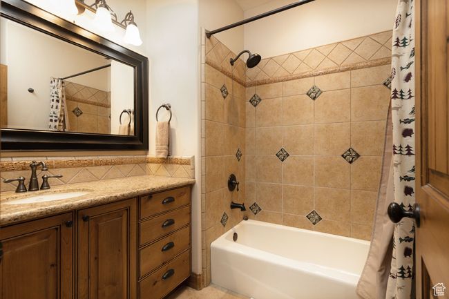 Bathroom with shower / bathtub combination with curtain, vanity, and tasteful backsplash | Image 36