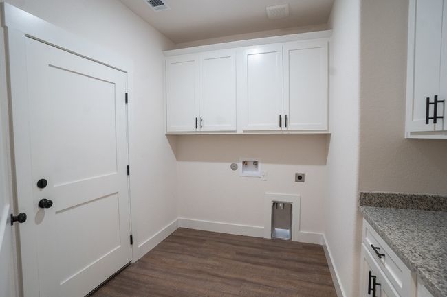 Laundry area with cabinet space, electric dryer hookup, hookup for a washing machine, dark wood-style flooring, and baseboards | Image 29