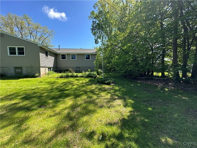 Back of home with a flagpole and nice seating area. | Image 18