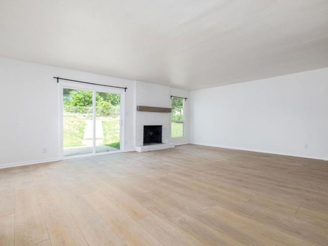 Unfurnished living room featuring light wood finished floors, a brick fireplace, and baseboards | Image 13