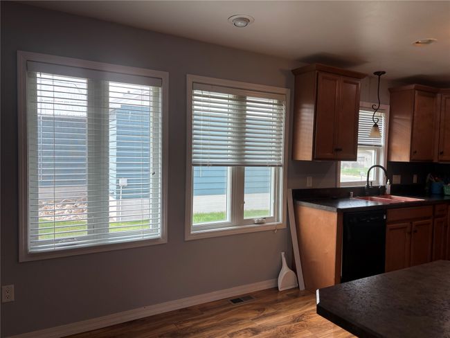 Kitchen with a sink, black dishwasher, dark countertops, baseboards, and wood finished floors | Image 12