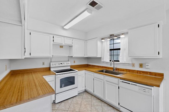 Kitchen featuring white appliances, a sink, white cabinets, and open shelves | Image 16